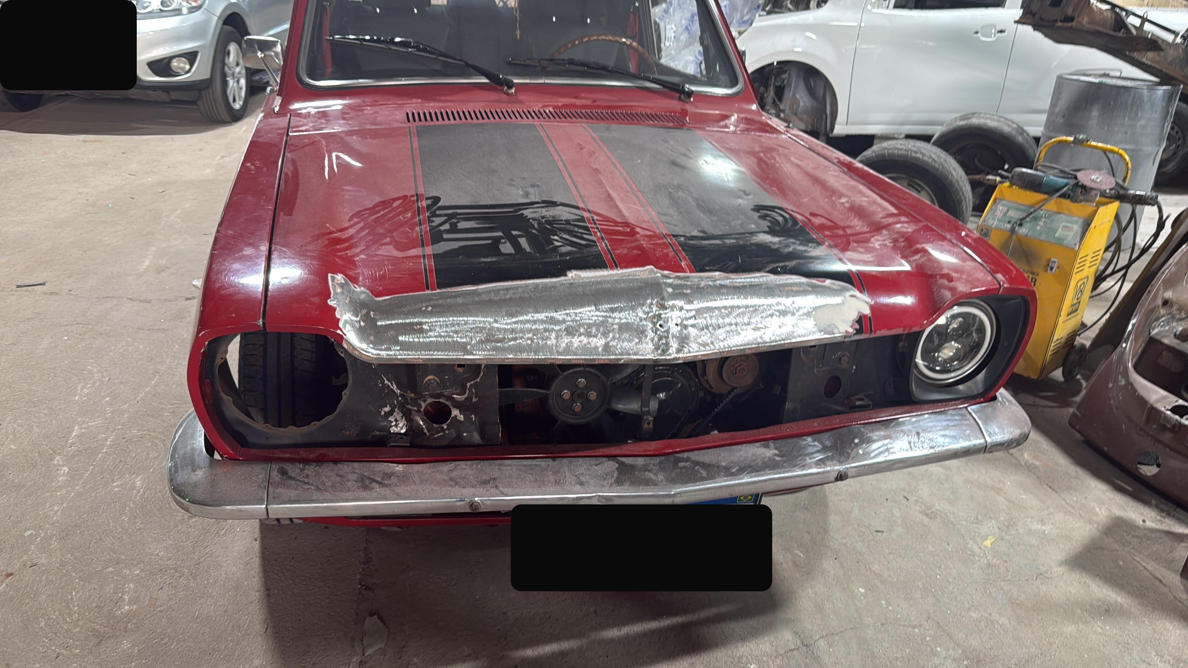 Carro clássico vermelho com frente danificada antes do reparo